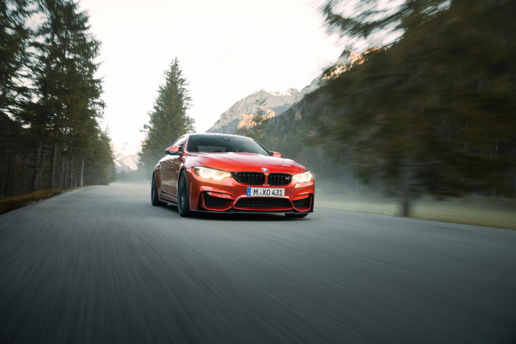 High-speed red sports car driving through scenic mountain road with blurred background